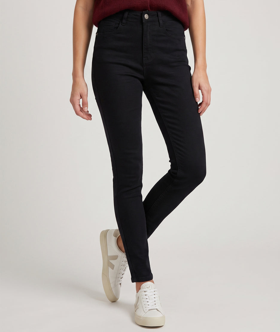 Pantalon slim femme noir taille haute porté avec gilet bordeaux et baskets blanches