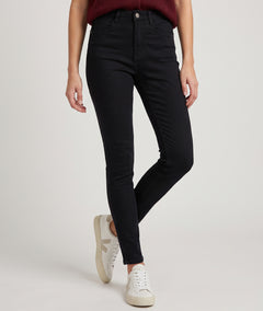 Pantalon slim femme noir taille haute porté avec gilet bordeaux et baskets blanches